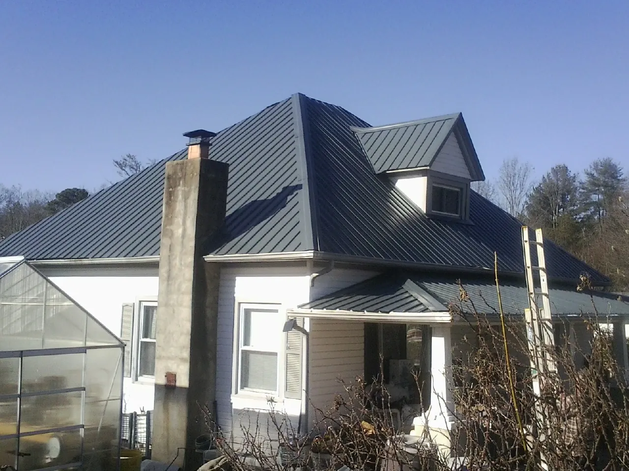Dark blue standing seam metal roof on a white farmhouse with dormer — Slate & Tile Roof Repair by Roofing Brothers in Kiel