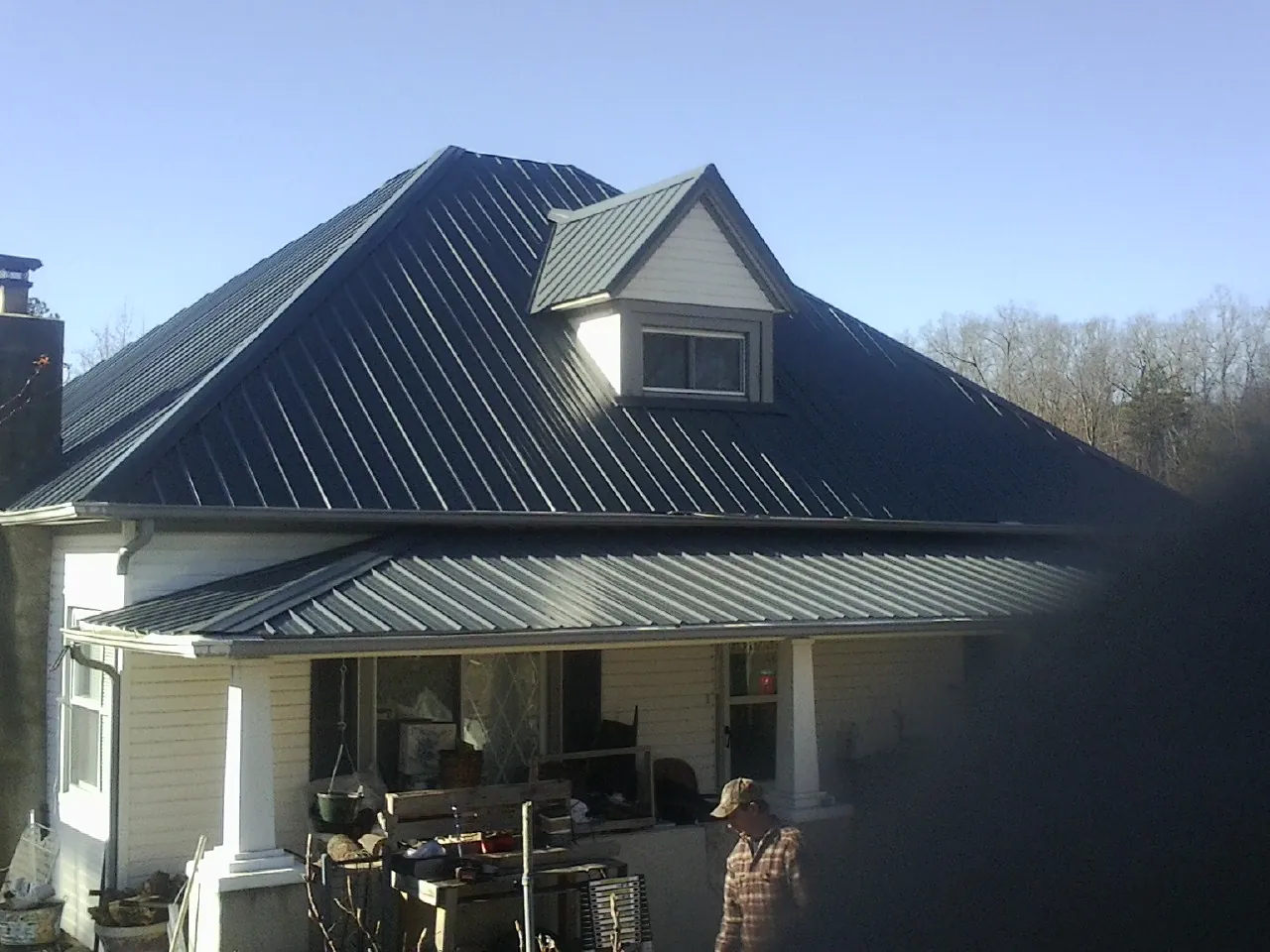 Dark blue standing seam metal roof with a dormer above a front porch in Kiel
