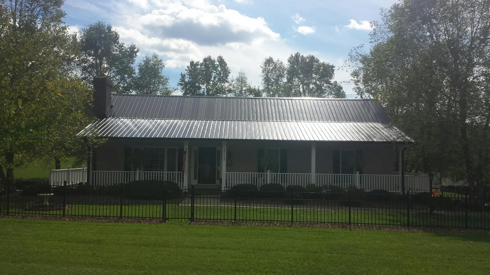 Gray metal roof on a brick ranch with a full width front porch — Gutter Guard Installation work by our crew in Kiel