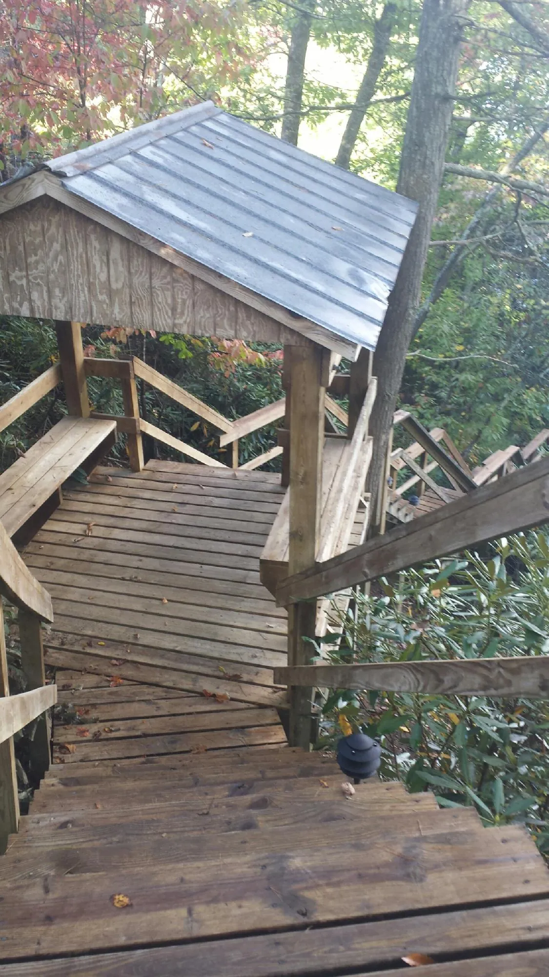 Metal roofed shelter over wooden steps on a wooded walkway — Skylight Repair & Installation work by our crew in Kiel