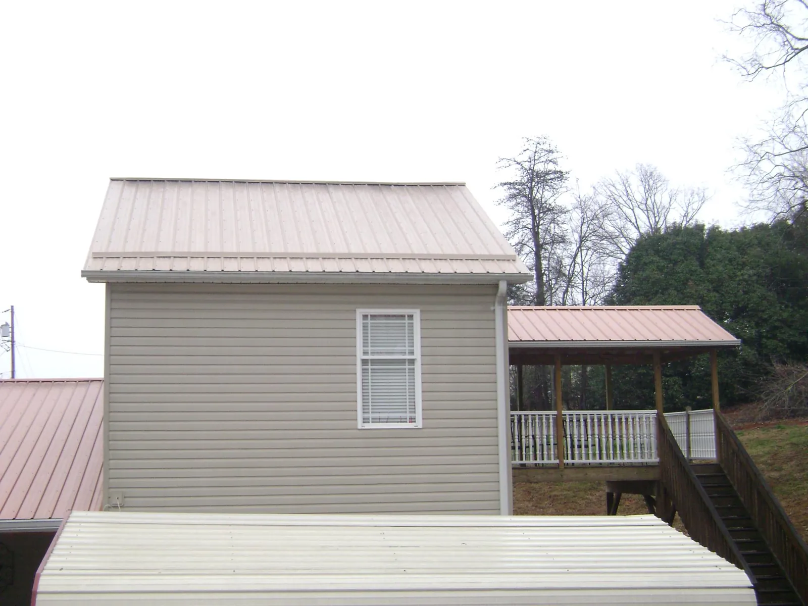 Tan metal roofs on a two story addition and attached porch, from a Roof Replacement job in Kiel
